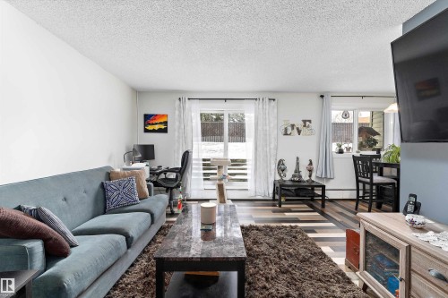 Living area featuring a textured ceiling, a desk, and wood finished floors - # 3 13450 Fort Road, Edmonton, AB - Indoor Photo Showing Living Room