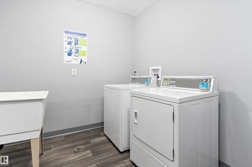 Community laundry with separate washer and dryer, wood finish floors, and a textured ceiling - # 3 13450 Fort Road, Edmonton, AB - Indoor Photo Showing Laundry Room