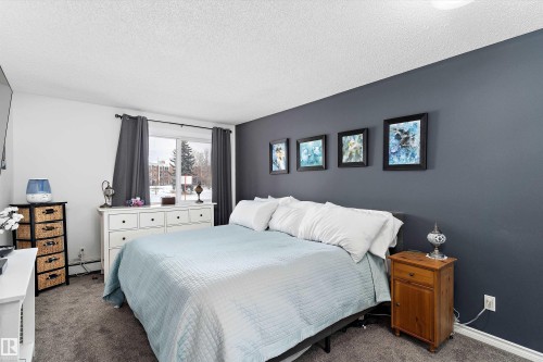 Bedroom with a textured ceiling, carpet, and a baseboard radiator - # 3 13450 Fort Road, Edmonton, AB - Indoor Photo Showing Bedroom