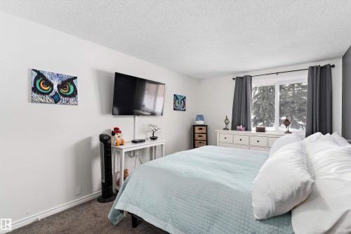 Carpeted bedroom featuring a textured ceiling and baseboards - # 3 13450 Fort Road, Edmonton, AB - Indoor Photo Showing Bedroom