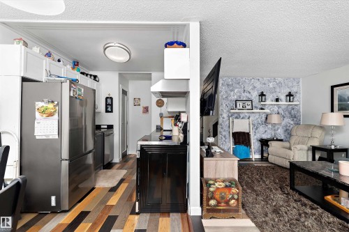Kitchen featuring stainless steel appliances, wood finished floors, white cabinets, extractor fan, and a textured ceiling - # 3 13450 Fort Road, Edmonton, AB - Indoor