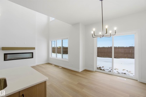 Unfurnished dining area featuring plenty of natural light, suspended lighting, and light wood-type flooring - 19348 29 Avenue, Edmonton, AB - Indoor Photo Showing Other Room With Fireplace