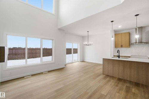 Kitchen with modern cabinets, hanging lights, light stone countertops, light wood-type flooring, and tasteful backsplash - 19348 29 Avenue, Edmonton, AB - Indoor Photo Showing Kitchen