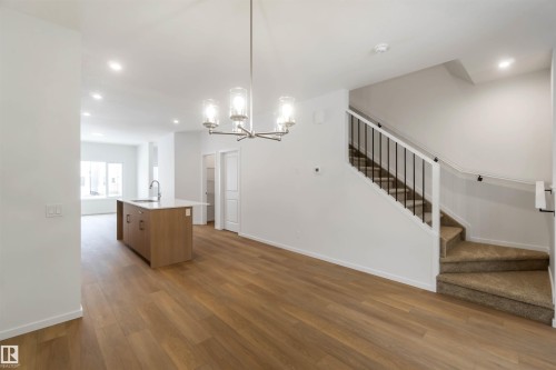 Kitchen featuring suspended lighting, a center island with sink, dark wood-style floors, open floor plan, and wood finish cabinets - 18912 28 Avenue, Edmonton, AB - Indoor Photo Showing Other Room