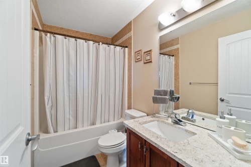 Bathroom featuring vanity, shower / bathtub combination with curtain, and a textured ceiling - 6116 53 Avenue, Beaumont, AB - Indoor Photo Showing Bathroom