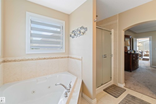 Bathroom with a shower stall, a tub with jets, light tile patterned flooring, and light colored carpet - 6116 53 Avenue, Beaumont, AB - Indoor Photo Showing Bathroom