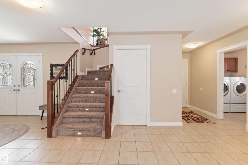 Foyer entrance featuring french doors, light tile patterned flooring, washer and dryer, and ornamental molding - 6116 53 Avenue, Beaumont, AB - Indoor