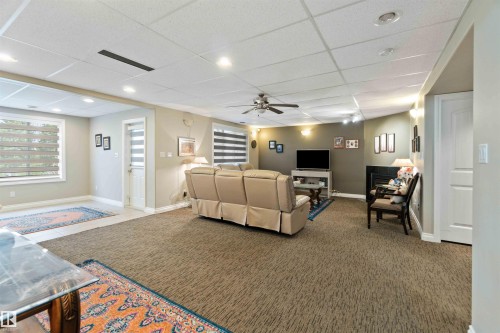 Living area with a paneled ceiling, a ceiling fan, carpet, a fireplace, and recessed lighting - 6116 53 Avenue, Beaumont, AB - Indoor