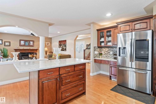 Kitchen featuring stainless steel fridge with ice dispenser, arched walkways, light stone counters, decorative backsplash, and recessed lighting - 6116 53 Avenue, Beaumont, AB - Indoor Photo Showing Kitchen