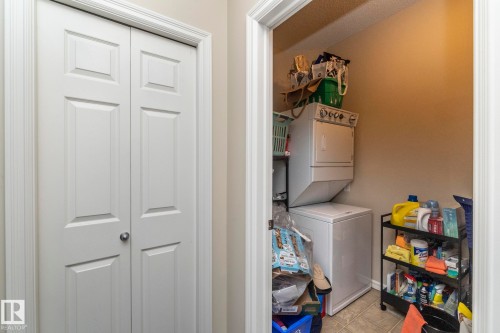 Laundry area with stacked washing machine and dryer and light tile patterned floors - 416 263 Macewan Road, Edmonton, AB - Indoor Photo Showing Laundry Room