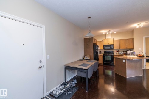 Kitchen featuring black appliances, pendant lighting, light brown cabinetry, light countertops, and a breakfast bar - 416 263 Macewan Road, Edmonton, AB - Indoor Photo Showing Kitchen