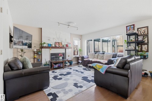 Living area featuring light wood-style floors, a glass covered fireplace, and rail lighting - 444 Breckenridge Lane Nw, Edmonton, AB - Indoor Photo Showing Living Room With Fireplace