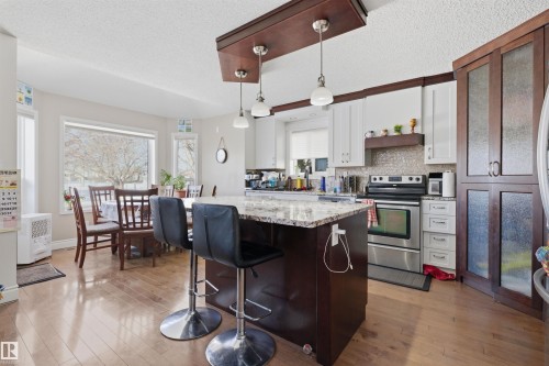 Kitchen with a kitchen breakfast bar, a kitchen island, dual tone cabinetry, electric range, and a textured ceiling - 444 Breckenridge Lane Nw, Edmonton, AB - Indoor Photo Showing Kitchen With Upgraded Kitchen