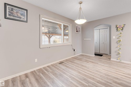 Unfurnished dining area featuring light wood finished floors, arched walkways, and a textured ceiling - 1157 37 Avenue, Edmonton, AB - Indoor Photo Showing Other Room