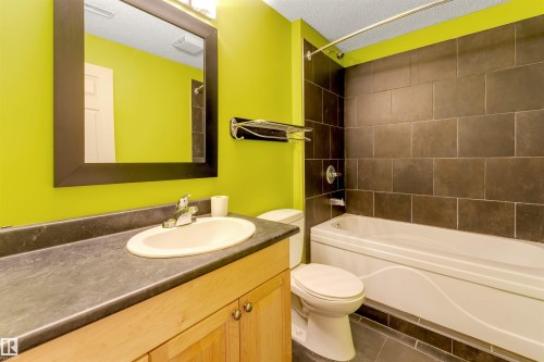 Full bath featuring vanity, a textured ceiling, bathtub / shower combination, and dark tile patterned floors - 1157 37 Avenue, Edmonton, AB - Indoor Photo Showing Bathroom