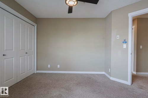 The room features neutral-toned walls, light-colored carpeting, a ceiling fan with integrated lighting, and white trim - 313 1510 Watt Drive, Edmonton, AB - Indoor Photo Showing Other Room