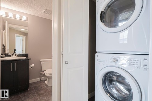The property features a bathroom with a dark wood vanity, a white sink, and a toilet - 313 1510 Watt Drive, Edmonton, AB - Indoor Photo Showing Laundry Room