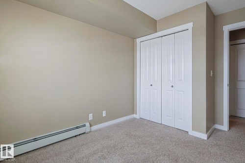 This room features light tan walls, a textured ceiling, and gray carpeted flooring - 313 1510 Watt Drive, Edmonton, AB - Indoor