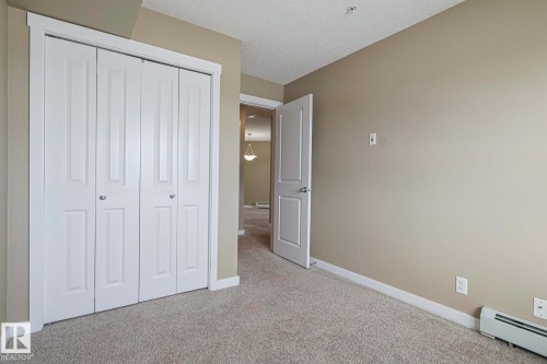 This room features plush carpet flooring, a closet with bi-fold doors, and neutral-toned walls - 313 1510 Watt Drive, Edmonton, AB - Indoor