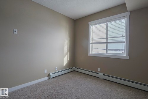 This room features neutral-toned walls, a window with blinds, and carpeting - 313 1510 Watt Drive, Edmonton, AB - Indoor Photo Showing Other Room