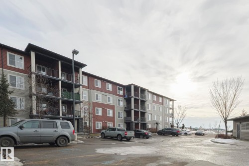 The property is a multi-story building featuring balconies with dark railings, a light-colored siding, and windows - 313 1510 Watt Drive, Edmonton, AB - Outdoor With Facade