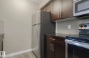 The kitchen features dark wood cabinetry, stainless steel appliances, and a tiled backsplash - 313 1510 Watt Drive, Edmonton, AB  - Indoor Photo Showing Kitchen 