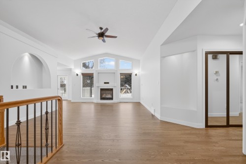 Unfurnished living room with a ceiling fan, lofted ceiling, light wood-type flooring, and a glass covered fireplace - 19 Country Lane, Stony Plain, AB - Indoor Photo Showing Other Room
