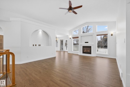 Unfurnished living room featuring ceiling fan, a glass covered fireplace, lofted ceiling, and dark wood finished floors - 19 Country Lane, Stony Plain, AB - Indoor Photo Showing Other Room With Fireplace