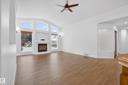 Unfurnished living room featuring vaulted ceiling, dark wood-style floors, a glass covered fireplace, and a ceiling fan - 19 Country Lane, Stony Plain, AB - Indoor Photo Showing Living Room With Fireplace