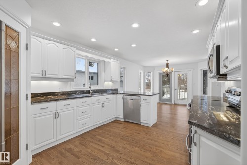 Kitchen featuring a peninsula, white cabinets, dark wood-style flooring, and stainless steel appliances - 19 Country Lane, Stony Plain, AB - Indoor Photo Showing Kitchen With Upgraded Kitchen
