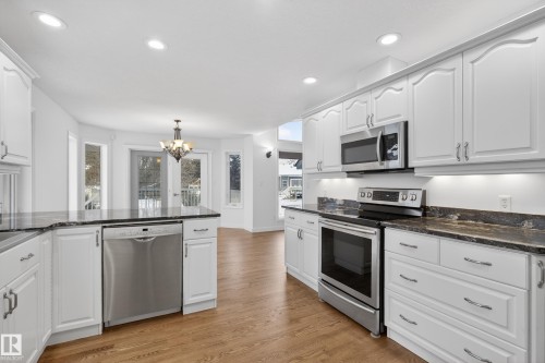 Kitchen with stainless steel appliances, dark stone counters, light wood-type flooring, and white cabinets - 19 Country Lane, Stony Plain, AB - Indoor Photo Showing Kitchen With Upgraded Kitchen