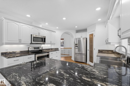 Kitchen with white cabinetry, stainless steel appliances, arched walkways, recessed lighting, and light wood-style floors - 19 Country Lane, Stony Plain, AB - Indoor Photo Showing Kitchen With Double Sink With Upgraded Kitchen