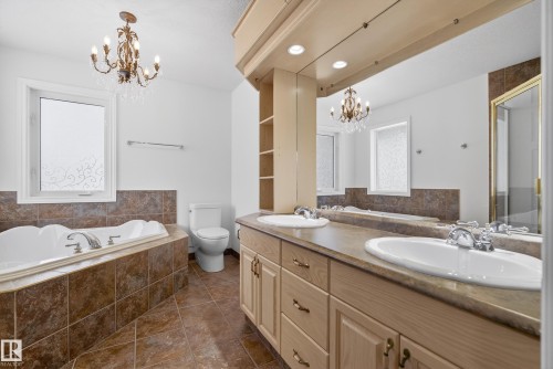 Bathroom with a chandelier, a garden tub, double vanity, and dark tile patterned floors - 19 Country Lane, Stony Plain, AB - Indoor Photo Showing Bathroom