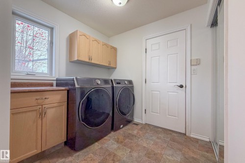 Laundry room with washer and clothes dryer, cabinet space, and stone finish flooring - 19 Country Lane, Stony Plain, AB - Indoor Photo Showing Laundry Room