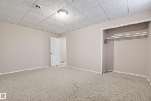 Unfurnished bedroom with a drop ceiling, carpet, and a closet - 19 Country Lane, Stony Plain, AB - Indoor Photo Showing Other Room