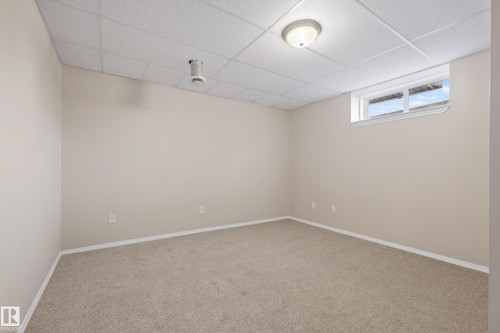 Carpeted spare room featuring a paneled ceiling and baseboards - 19 Country Lane, Stony Plain, AB - Indoor Photo Showing Other Room