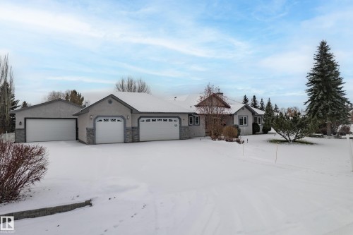 Ranch-style house featuring stone siding, a garage, and stucco siding - 19 Country Lane, Stony Plain, AB - Outdoor