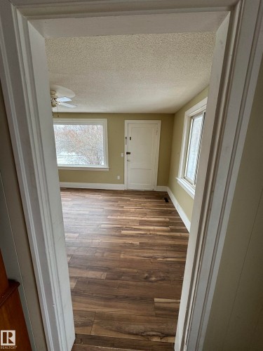 The property features wood-look flooring, light-colored walls, and large windows providing natural light - 4906 48 Street, Thorsby, AB - Indoor Photo Showing Other Room