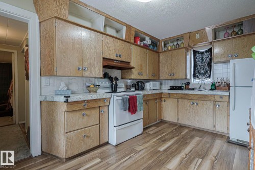 Kitchen featuring white appliances, light countertops, light wood-style floors, backsplash, and open shelves - 4906 48 Street, Thorsby, AB - Indoor Photo Showing Kitchen