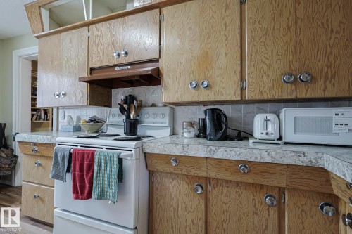 Kitchen with white appliances, decorative backsplash, and wood finish cabinets - 4906 48 Street, Thorsby, AB - Indoor Photo Showing Kitchen
