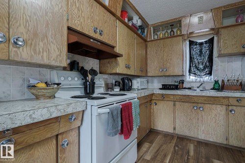Kitchen featuring white appliances, light countertops, dark wood-type flooring, backsplash, and a textured ceiling - 4906 48 Street, Thorsby, AB - Indoor Photo Showing Kitchen