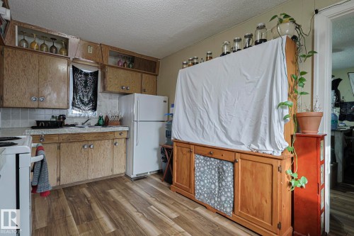 Kitchen featuring white appliances, light countertops, dark wood-type flooring, a textured ceiling, and decorative backsplash - 4906 48 Street, Thorsby, AB - Indoor Photo Showing Kitchen