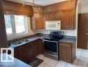 Kitchen with stainless steel electric range, white microwave, dark countertops, light tile patterned floors, and a textured ceiling - 11 Campbell, Stony Plain, AB  - Indoor Photo Showing Kitchen With Double Sink 