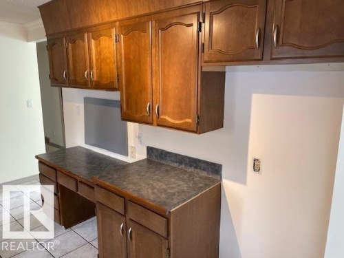 Kitchen with wood finish cabinetry, dark countertops, and light tile patterned floors - 11 Campbell, Stony Plain, AB - Indoor Photo Showing Kitchen