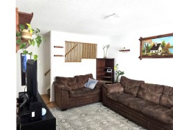 Living area featuring white walls, a textured ceiling, and a light-colored area rug - 