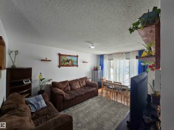 The living area features white walls, a textured ceiling, and hardwood flooring in the dining space - 
