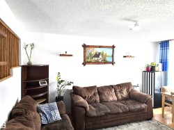 Living area featuring white walls, a textured ceiling, and a ceiling fan - 