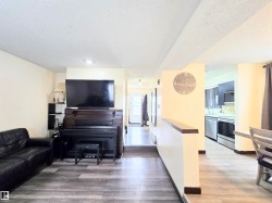 Living area with light wood-type flooring, a textured ceiling, and recessed lighting - 