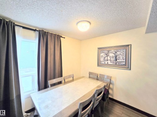 Dining room featuring a textured ceiling and dark wood finished floors - 2 4403 Riverbend Road, Edmonton, AB - Indoor Photo Showing Dining Room