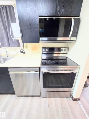 Kitchen with stainless steel appliances, light countertops, and light wood finished floors - 2 4403 Riverbend Road, Edmonton, AB - Indoor Photo Showing Kitchen